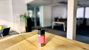 Kaffee-Thermosbecher auf dem hohen Tisch im leeren Coworking Space.